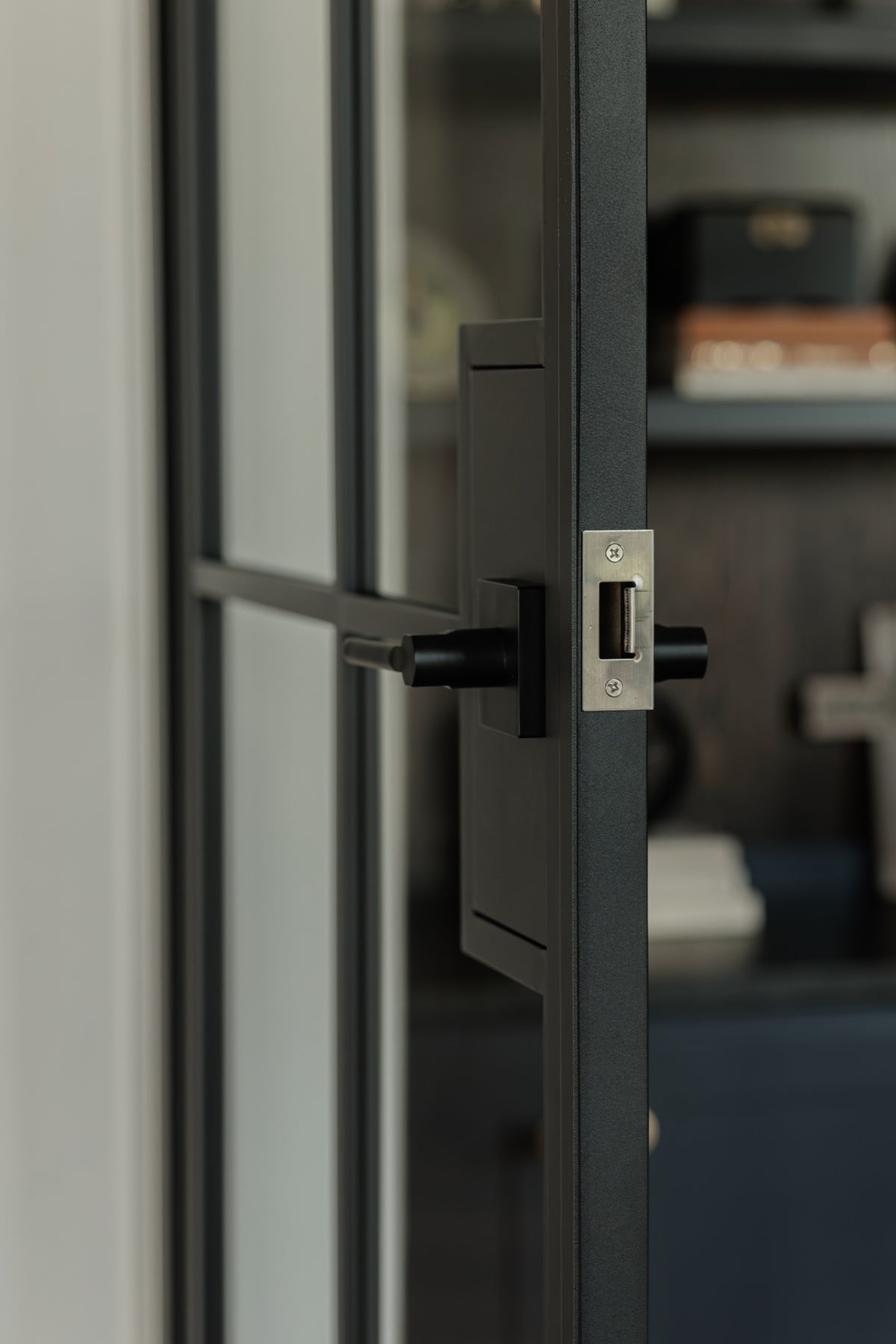 Matte black lever handle with lock on an 8 Lite steel French door, close-up